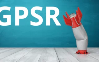 Grafik zur EU-Produktsicherheitsverordnung (GPSR): Eine humorvolle Darstellung einer schiefgegangenen Rakete, die auf einem hellen Holzboden steht, vor einem türkisfarbenen Hintergrund. Der Text 'GPSR' hebt die thematische Verbindung zur neuen Produktsicherheitsverordnung hervor.